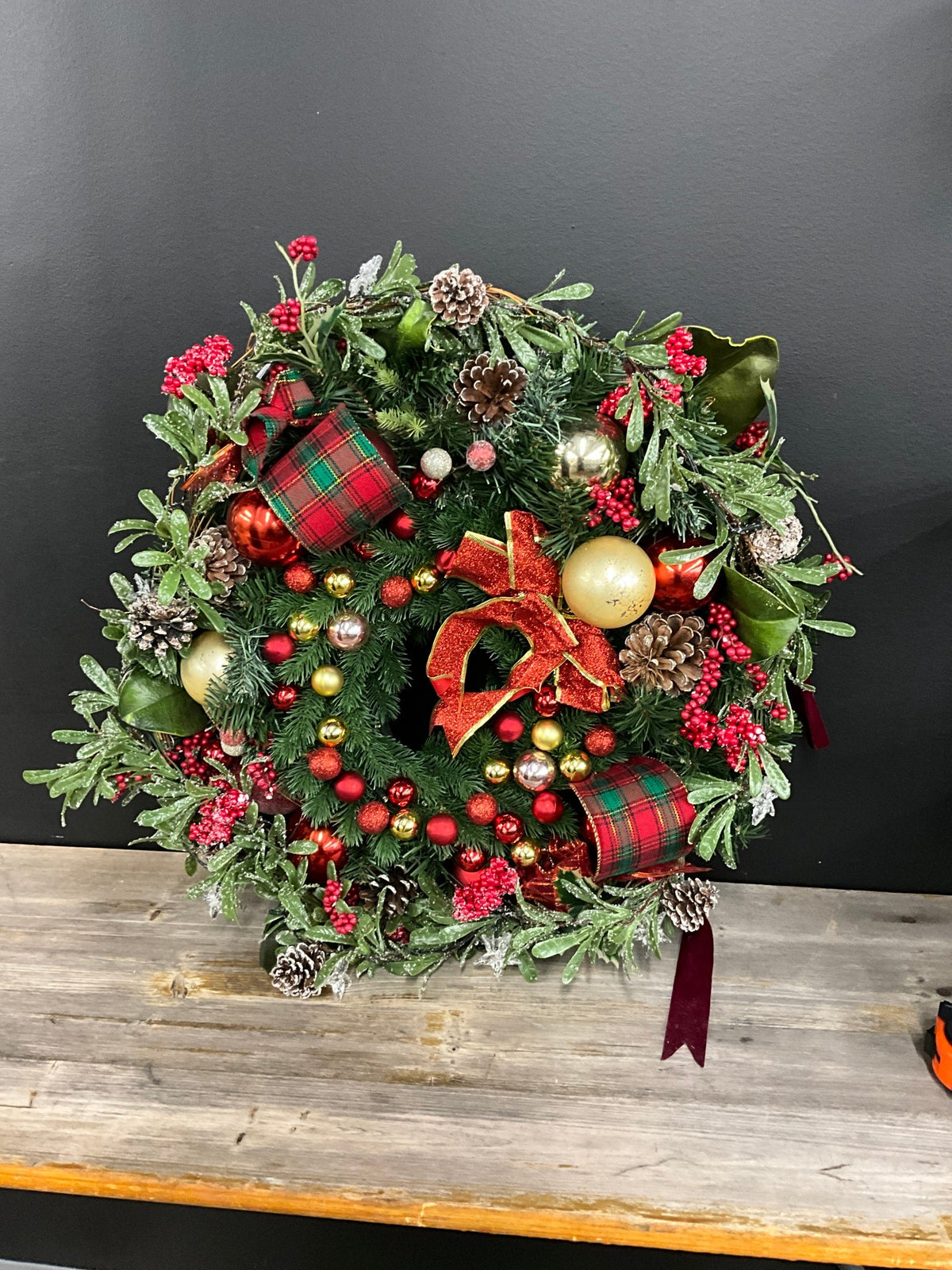 Christmas wreath with tartan ribbon, pine cones and red and gold ornaments
